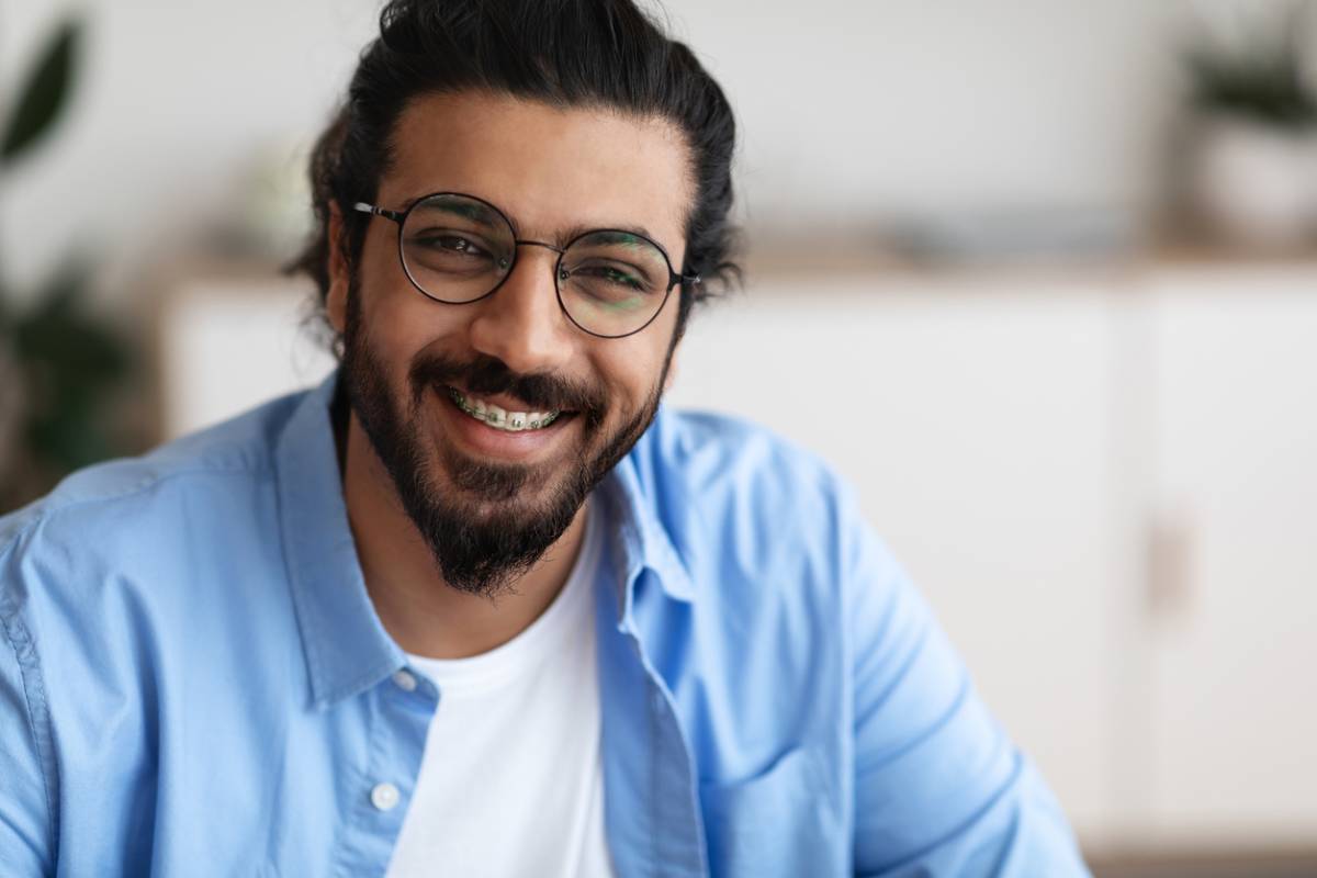 Man smiling with braces to straighten his teeth