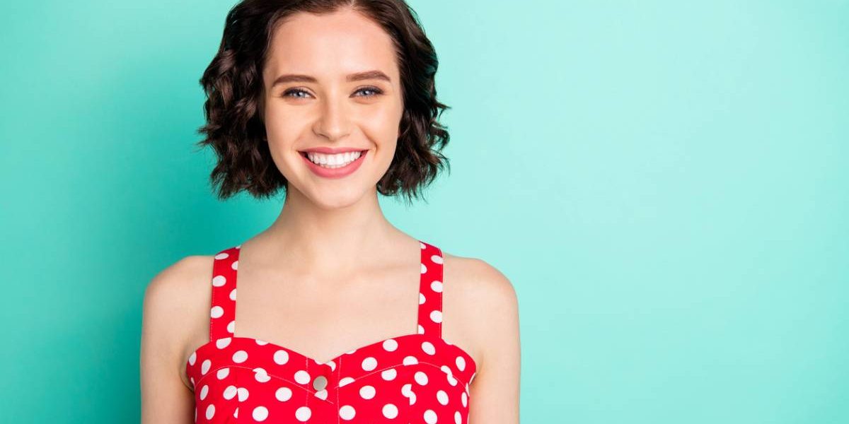 Woman smiling in front of teal background.